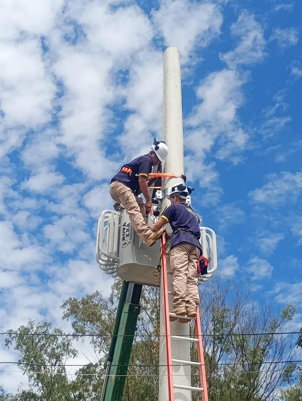 Equipe trabalhando em poste com cesto aéreo